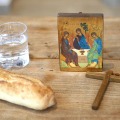 Brød, vand, kors og ikon på træbord.